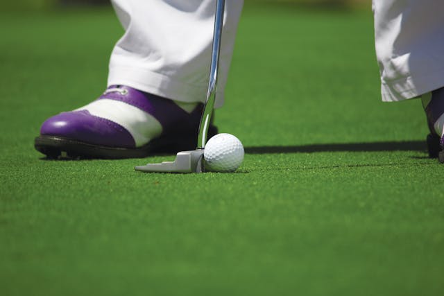 Golfer lining up a putt – Sports psychology hypnosis for focus, mental toughness, and peak performance training.