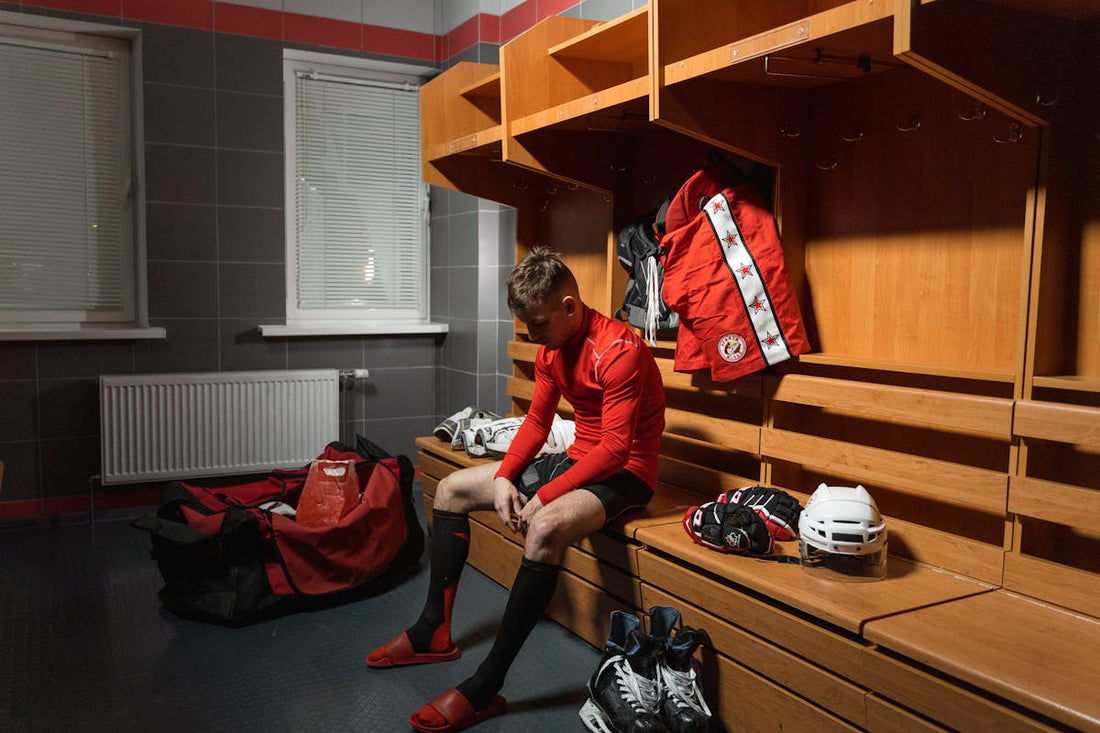 Young athlete sitting alone in a locker room reflecting after a difficult sports season, representing mental recovery and sports psychology.