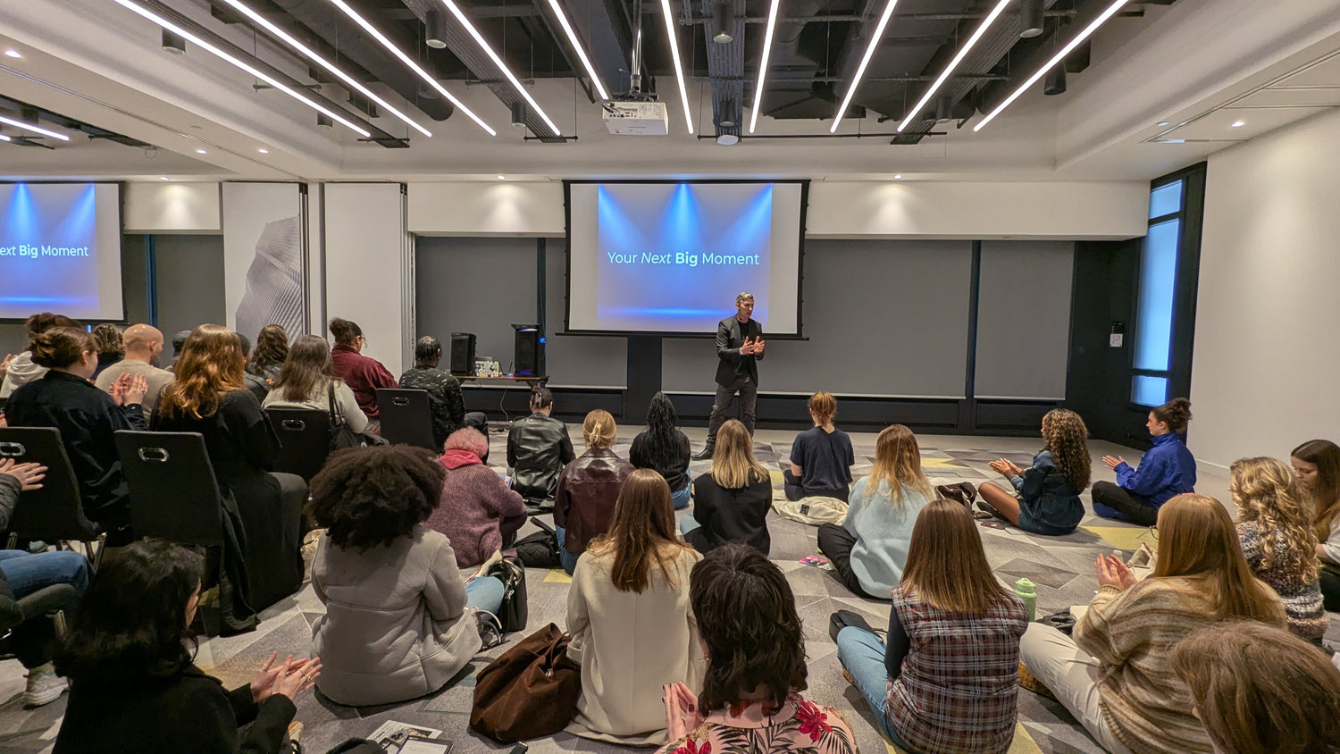 Neil Sunley giving a presentation to an audience in a modern conference room.