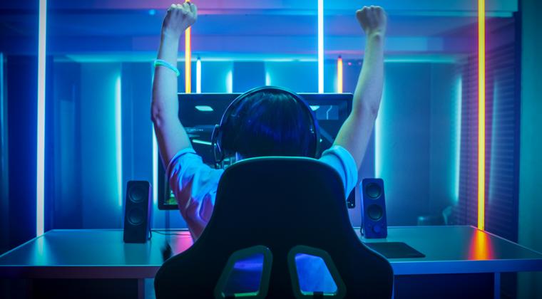 Gamer sat at a gaming table hands in the air celebrating a win